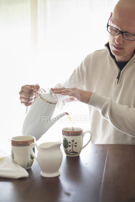 Mann gießt eine Tasse Kaffee ein. — Stockfoto
