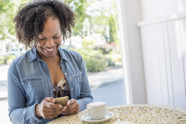 Женщина держит смартфон в кафе — стоковое фото