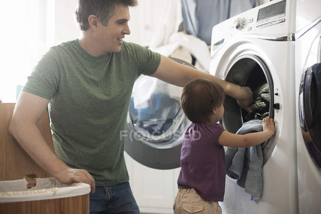 Hombre y un niño pequeño vaciando la ropa - foto de stock
