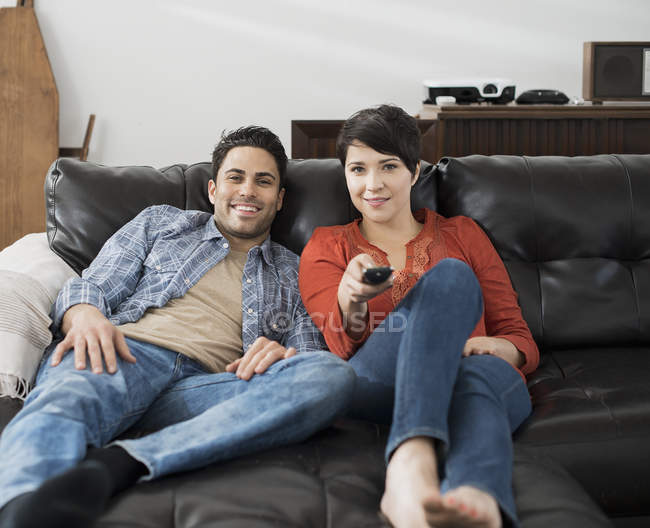 Couple using the remote control for the tv. — Stock Photo