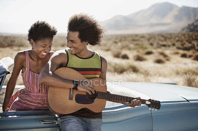 Coppia in piedi accanto ad una cabriolet blu pallido — Foto stock