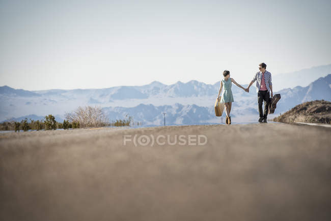 Casal em uma estrada de asfalto no deserto — Fotografia de Stock