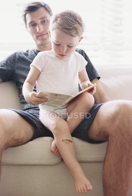 Uomo seduto su un divano con suo figlio — Foto stock