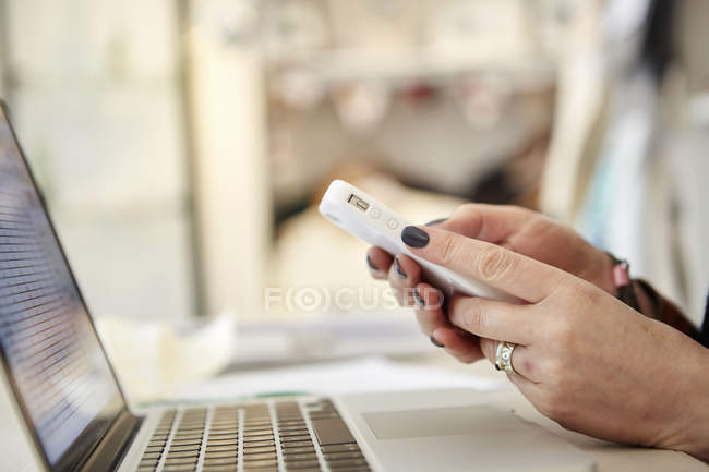 Femme utilisant un ordinateur portable et un smartphone — Photo de stock