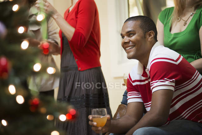 Adultos en la habitación alrededor del árbol de Navidad - foto de stock