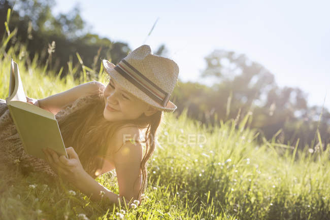 Girl lying on the grass reading a book — Stock Photo