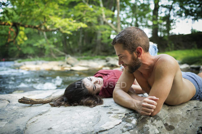 Homem e mulher deitados sobre rochas — Fotografia de Stock