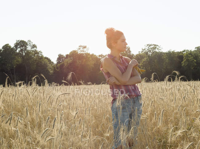Mulher de pé em um campo de trigo — Fotografia de Stock
