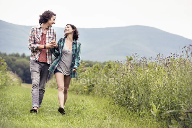 Homem e mulher caminhando através de um prado — Fotografia de Stock