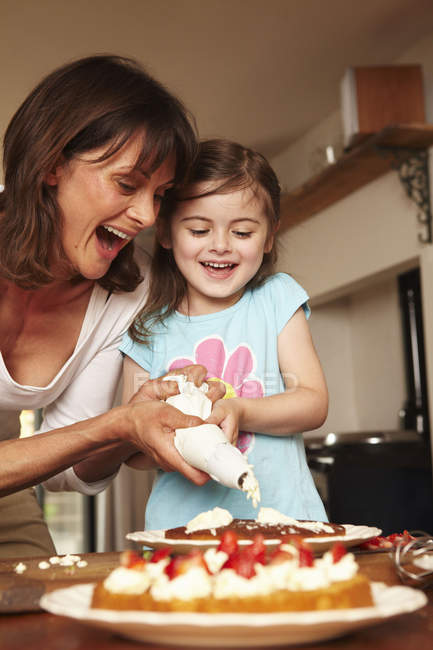 Mãe e filha gelar um bolo — Fotografia de Stock