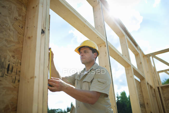 Hombre midiendo tablón de madera - foto de stock