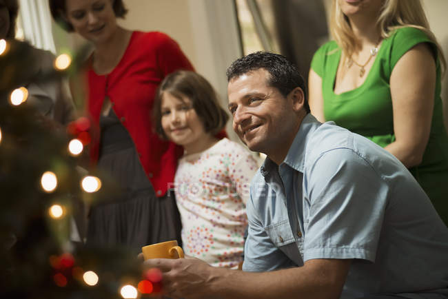 Adultos y niños en la habitación alrededor del árbol de Navidad - foto de stock