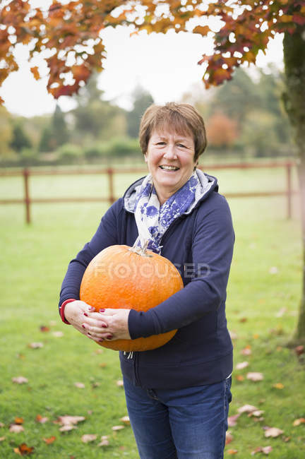 Woman holding a large orange pumpkin. — Stock Photo