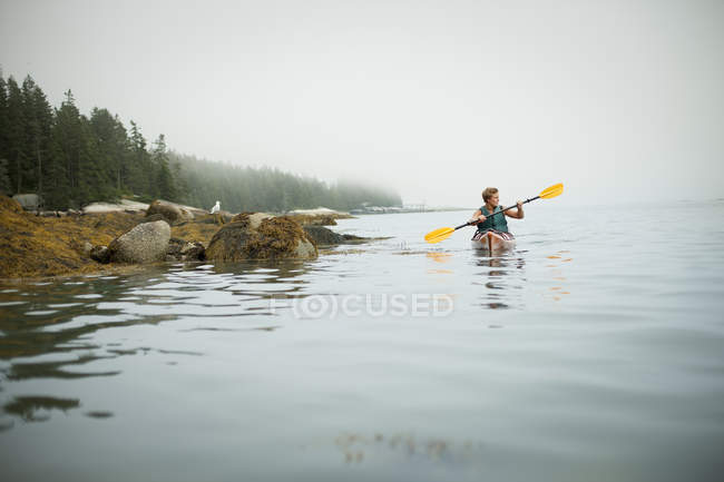 Hombre remando un kayak en aguas tranquilas - foto de stock