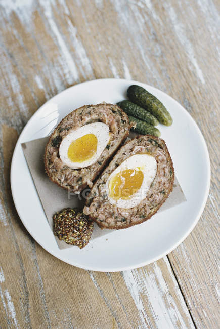 Scotch egg cut in half with garnishes. — Stock Photo
