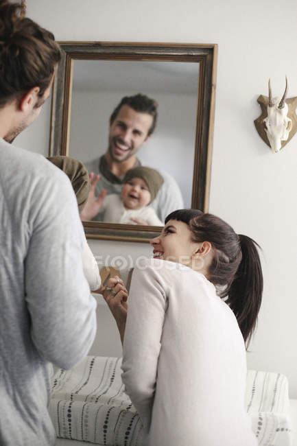 Родители со своим ребенком, смотрящие в зеркало . — стоковое фото