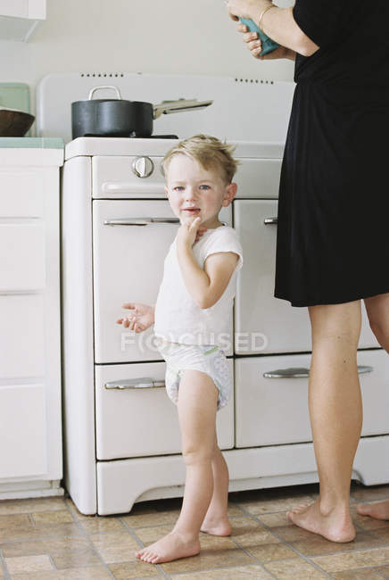 Menino de pé descalço em uma cozinha . — Fotografia de Stock