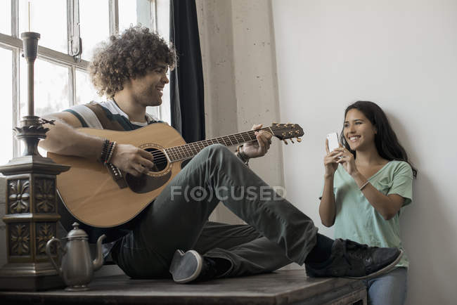 Homme jouant de la guitare et une femme avec téléphone — Photo de stock