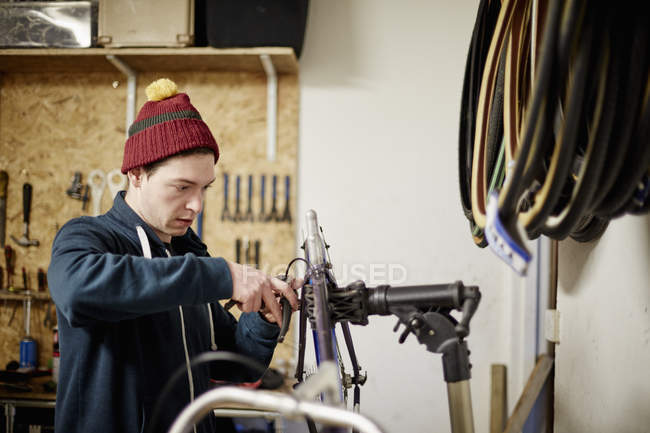 Человек ремонтирует велосипед в веломастерской — стоковое фото