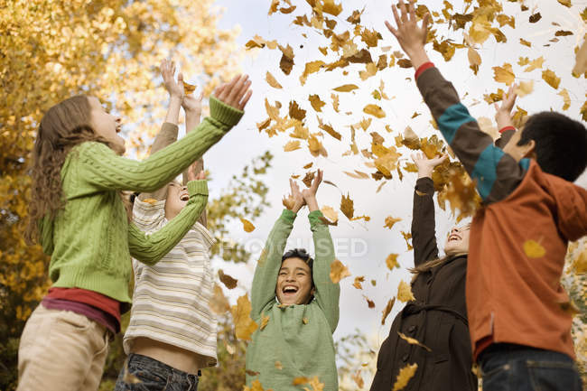 Діти кидають опале осіннє листя — стокове фото