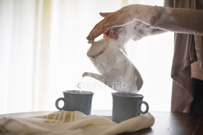 Frau gießt Kaffee in Becher. — Stockfoto