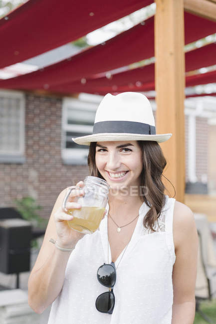 Frau steht in einem Garten und hält einen Drink. — Stockfoto