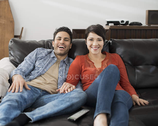 Casal sentado em um sofá e assistindo tv . — Fotografia de Stock