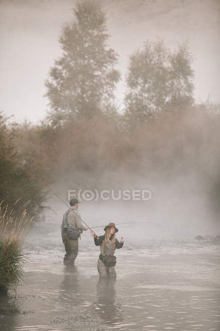 Couple flyfishing in a river. — Stock Photo