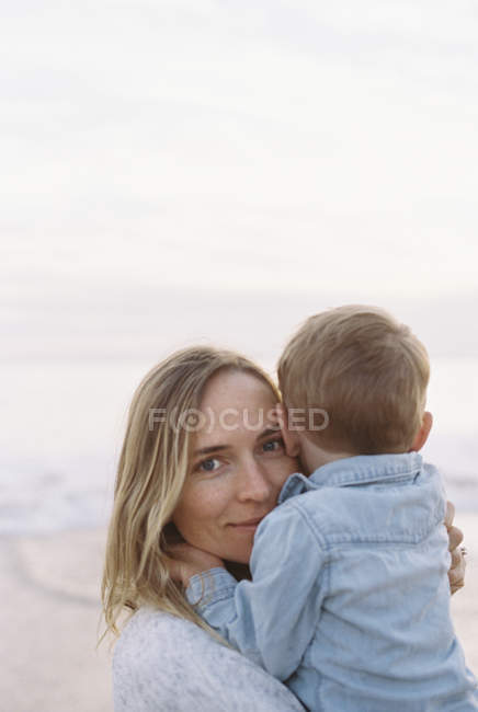 Mujer con hijo en una playa de arena - foto de stock