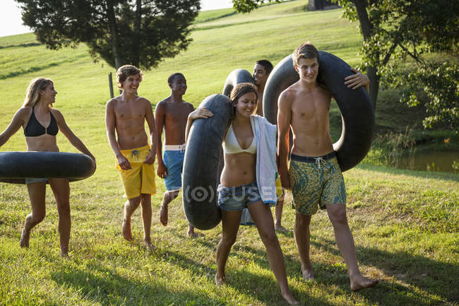 Niños y niñas, sosteniendo toallas y flotadores de natación - foto de stock