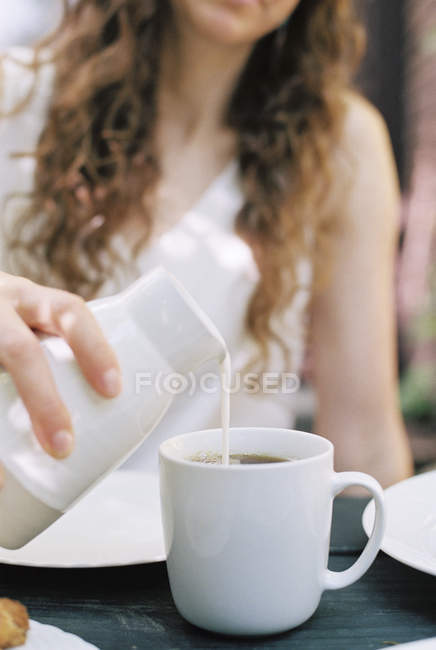 Mujer vertiendo leche - foto de stock