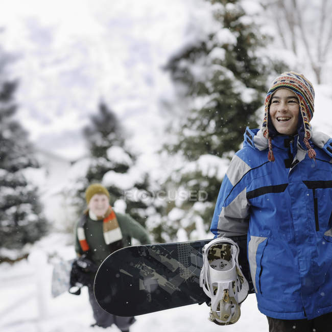 Jeune garçon portant un snowboard — Photo de stock