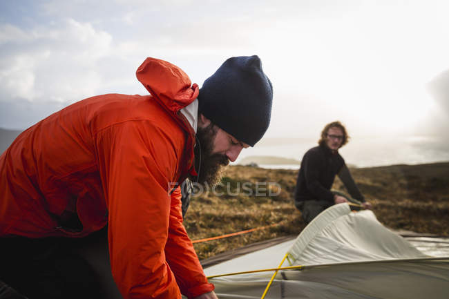 Homens segurando e montando uma pequena tenda — Fotografia de Stock