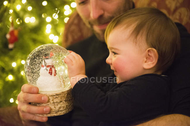 Padre y bebé mirando bola de nieve - foto de stock