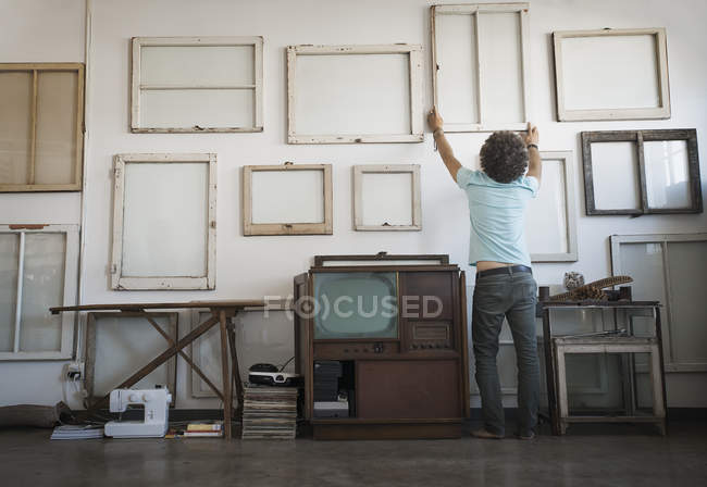Man hanging framed picture canvases — Stock Photo
