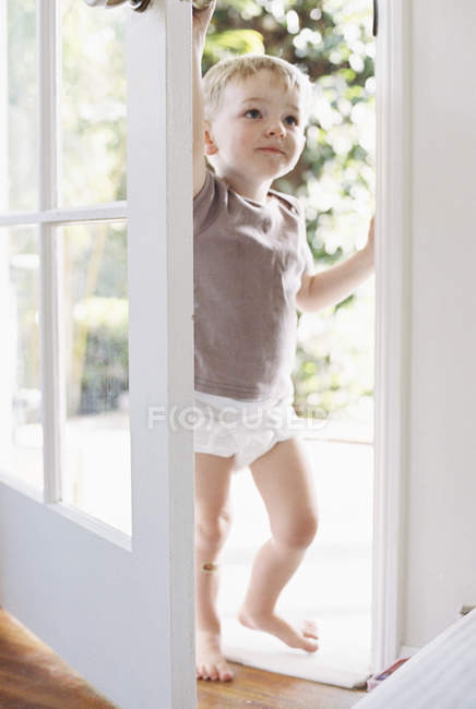 Kleiner Junge, der eine Tür öffnet. — Stockfoto
