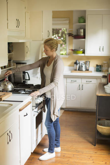 Mujer de pie en una cocina - foto de stock