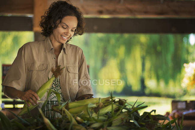 Mujer con un montón de maíz - foto de stock