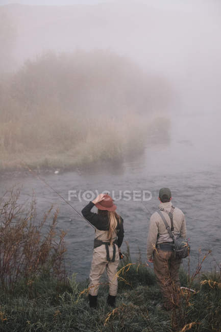People on riverbank looking across the water. — Stock Photo