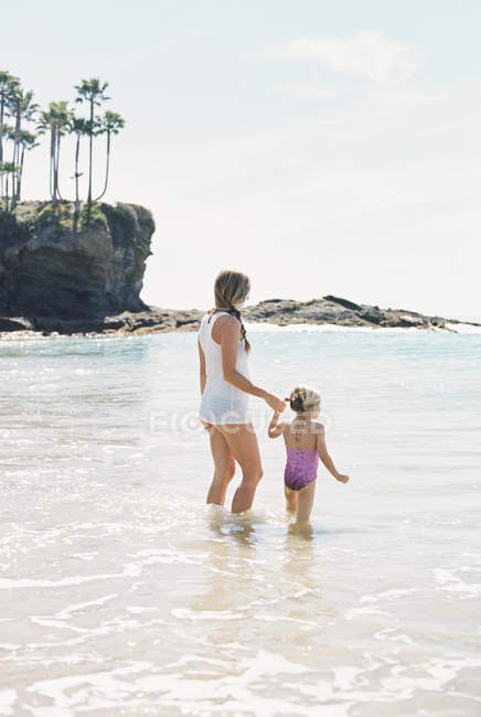 Mujer con hija en la playa . - foto de stock
