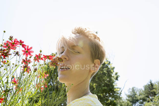 Mujer de pie cara a cara con gama flores Rudbeckia - foto de stock