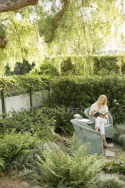 Woman sitting in a garden, reading — Stock Photo