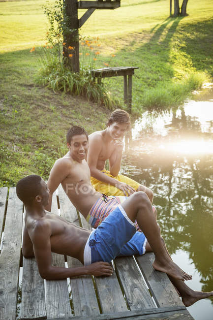 Chicos sentados en un embarcadero de madera - foto de stock