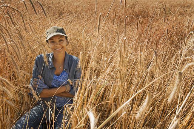 Женщина, сидящая в поле и улыбающаяся — стоковое фото