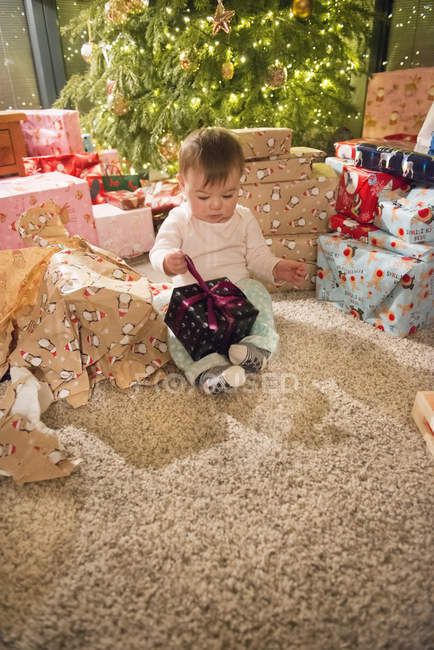 Menina sentada entre pilha de presentes — Fotografia de Stock