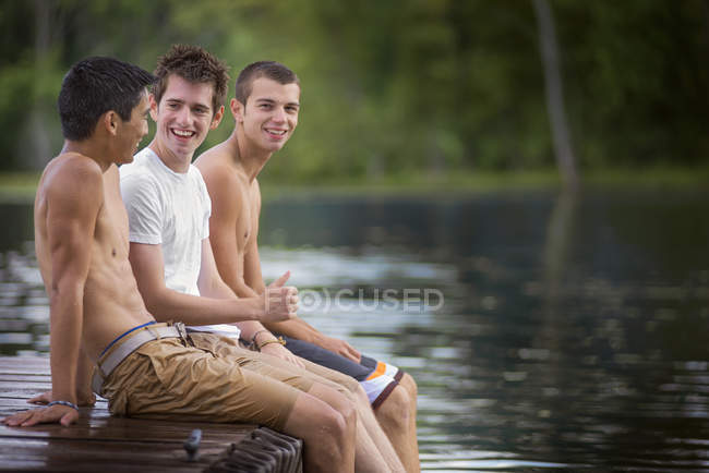 Meninos sentados no molhe ao lado do lago — Fotografia de Stock