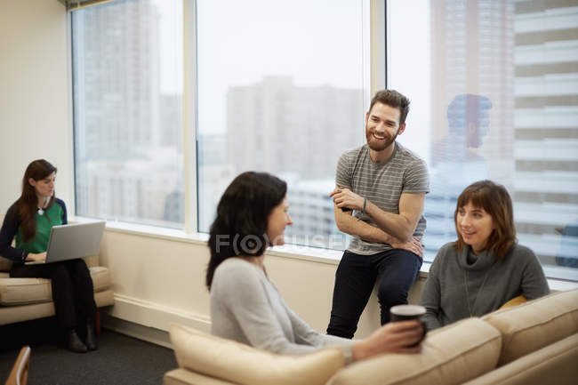 Three people by a window in an office — Stock Photo