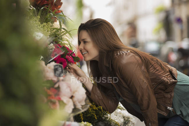 Woman bending to smell the scent of flowers — Stock Photo