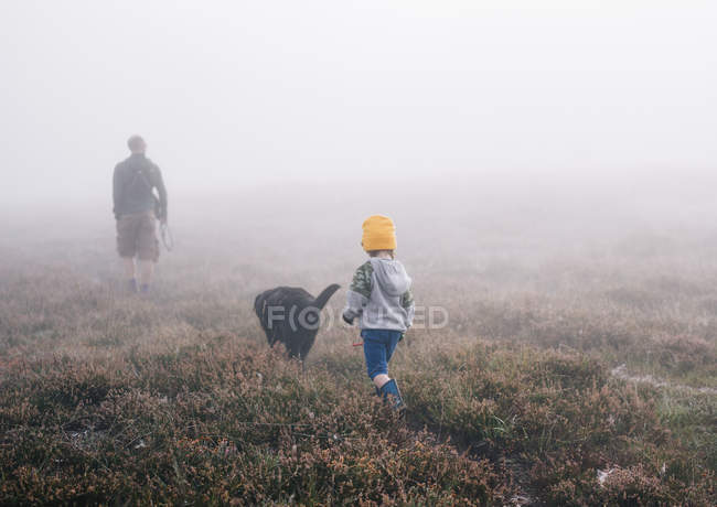 Adulte et un enfant avec un chien dans la brume d'automne . — Photo de stock