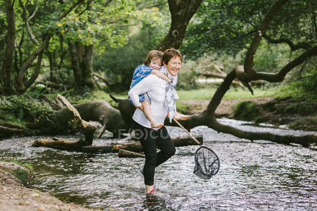 Mulher dando um menino um piggyback — Fotografia de Stock